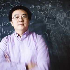 Xianyi Zeng portrait in front if a black board.